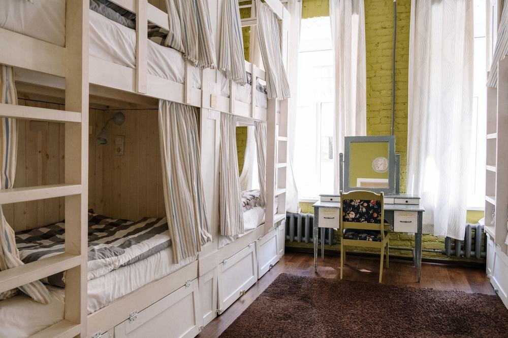 Schludny pokój w hostelu z drewnianymi łóżkami piętrowymi i szafkami