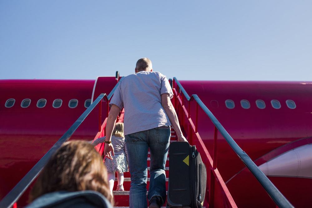 Schody do samolotu na płycie lotniska i pasażerowie wchodzący na pokład widziani od tyłu