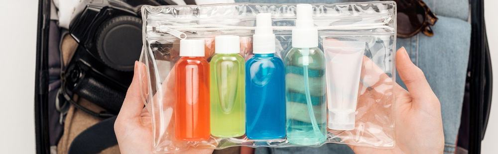Kosmetyki w małych opakowaniach podróżnych w przezroczystej plastikowej torebce